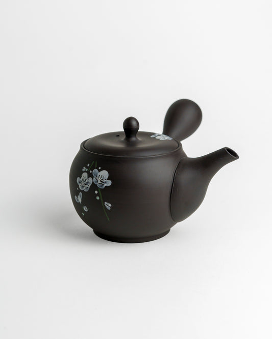 Schwarze Teekanne mit weißen Blüten