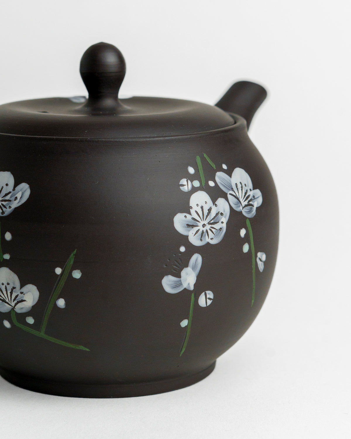Schwarze Teekanne mit weißen Blüten
