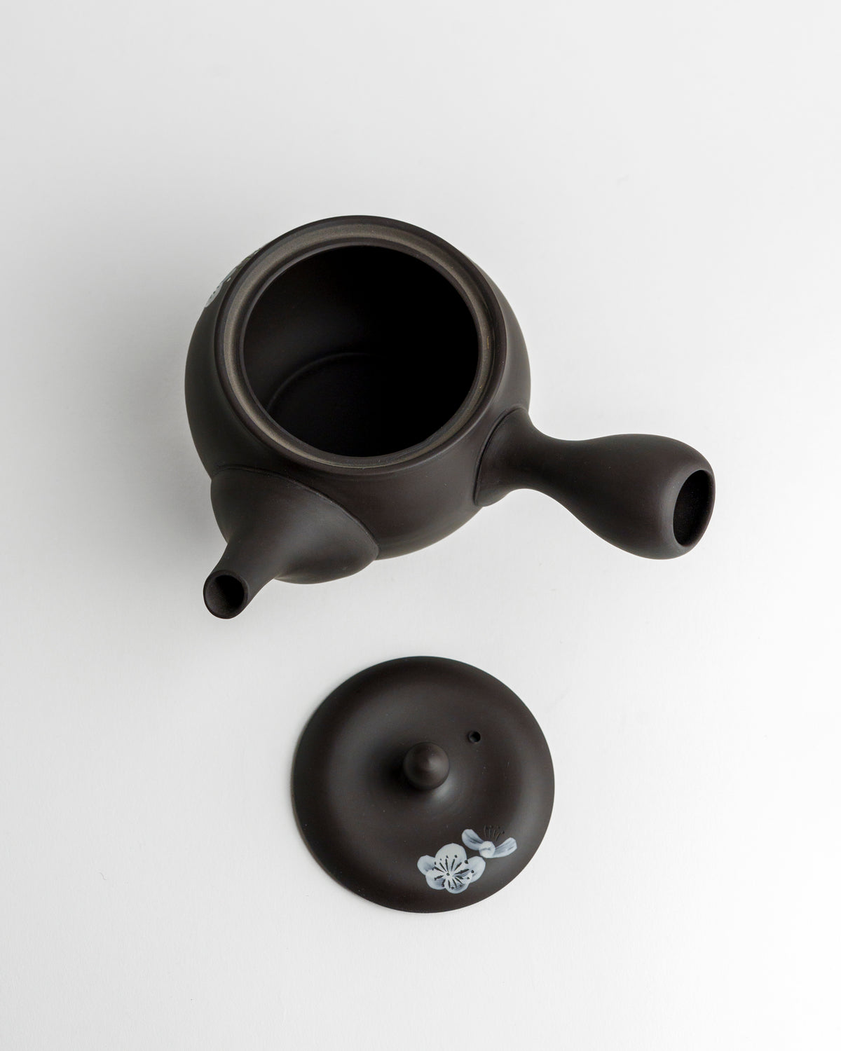 Schwarze Teekanne mit weißen Blüten