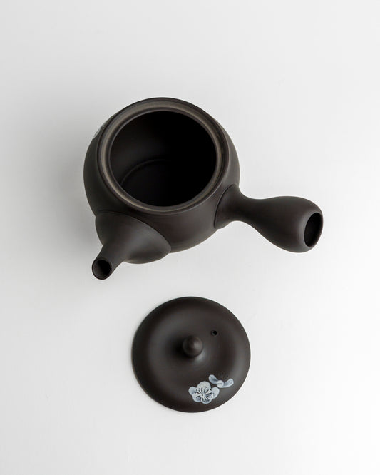 Schwarze Teekanne mit weißen Blüten