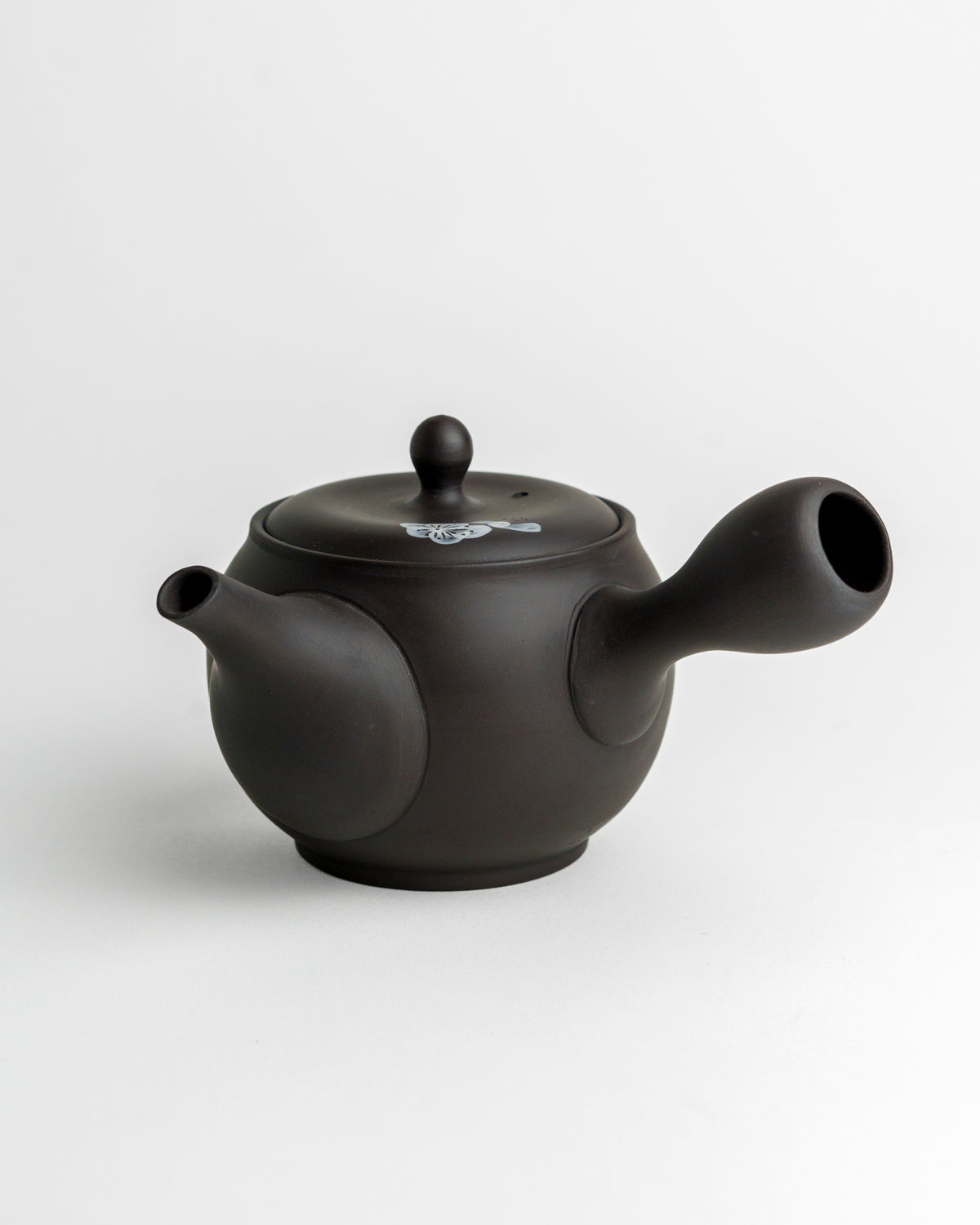 Schwarze Teekanne mit weißen Blüten